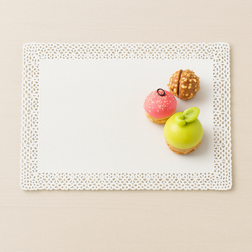 Carta pizzo bianca stesa con sopra tre pasticcini colorati